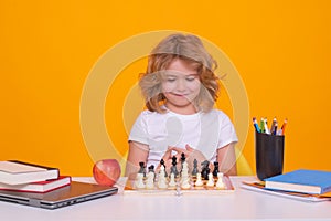 Child play chess on studio background. Kid playing chess. Clever child thinking about chess. Kids early development.