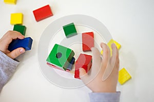 Child play with colored wooden brick shapes