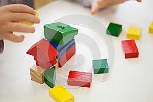 Child play with colored wooden brick shapes