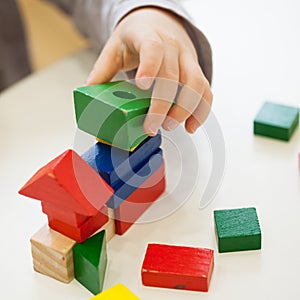 Child play with colored wooden brick shapes