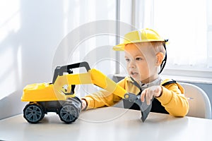 Child play with excavator at home, dreams to be an engineer. Little builder. Education, and imagination, purposefulness