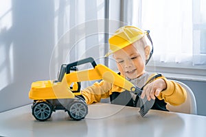 Child play with excavator at home, dreams to be an engineer. Little builder. Education, and imagination, purposefulness