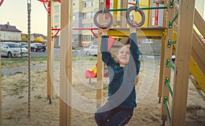 Child play and frolic on the Playground. A girl in a blue sweater plays in the yard of a multi storey building.