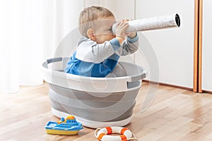 Child play in handmade ship with spyglass in hands, looking far, exploring horizon. Summer vacation and travel adventure