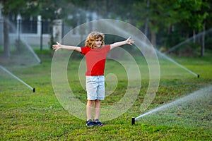 Child play near automatic sprayers in the garden. Watering in the garden. Kid freshness of nature. Automatic lawn