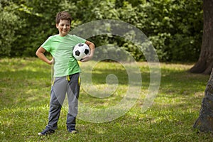 Child play soccer player. Boy with ball on green grass