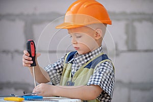 Child play with supplies, tools saw, hammer, screwdriver, helmet, builder, carpenter. Kids playing in the profession