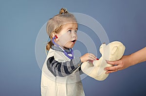 Child play veterinarian with teddy bear in mothers hand