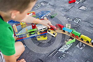Child play with wooden train, build toy railroad at home or kindergarten. Toddler kid play with wooden train