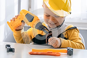 Child play with work tools at home, dreams to be an engineer. Little boy builder. Education, and imagination