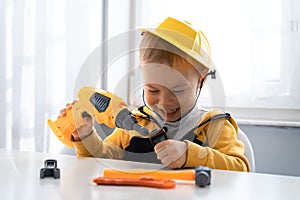 Child play with work tools at home, dreams to be an engineer. Little boy builder. Education, and imagination