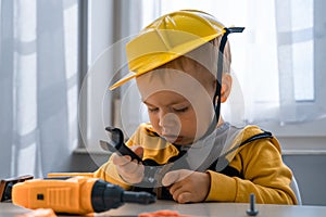 Child play with work tools at home, dreams to be an engineer. Little boy builder. Education, and imagination