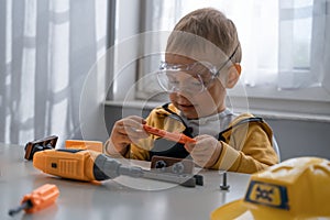 Child play with work tools at home, dreams to be an engineer. Little boy builder. Education, and imagination