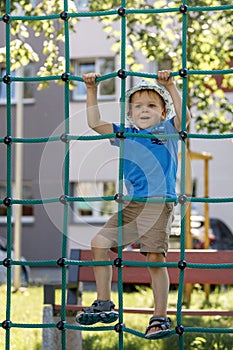 Boy In Adventure Park having fun in high wire park. Male toddler on climbing net