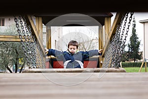 Child in the playground passing over the chain bridge
