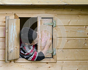 Child in playhouse drawing with chalk