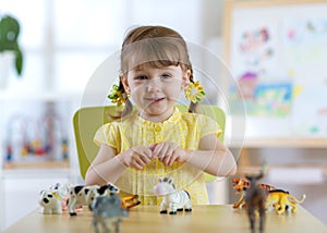 Child playing with animal toys at table in kindergarten or home