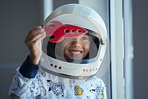 Child playing with astronaut helmet and toy rocket