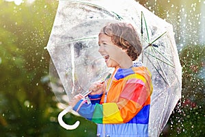 Child playing in autumn rain. Kid with umbrella