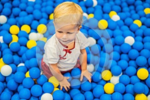 Child playing in ball pit. Colorful toys for kids. Kindergarten or preschool play room. Toddler kid at day care indoor