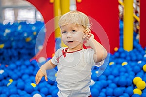 Child playing in ball pit. Colorful toys for kids. Kindergarten or preschool play room. Toddler kid at day care indoor