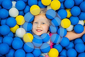 Child playing in ball pit. Colorful toys for kids. Kindergarten or preschool play room. Toddler kid at day care indoor