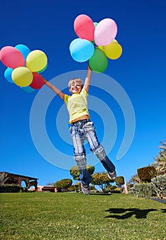 Child playing with balloons in park.