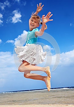 Child playing on beach aganiist blue sky.