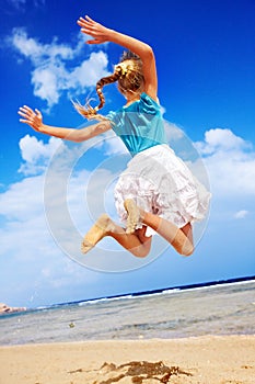 Child playing on beach aganist blue sky.