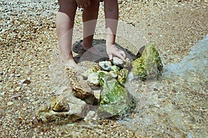 Child playing on the beach and building stone tower. stones on the beach