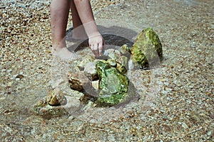 Child playing on the beach and building stone tower. stones on the beach