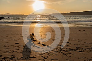 Child playing on the beach in the sand during the beautiful winter sunset