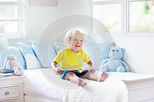 Child playing in bed. Kids room. Baby boy at home