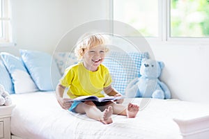 Child playing in bed. Kids room. Baby boy at home