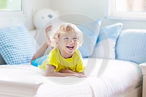 Child playing in bed. Kids room. Baby boy at home