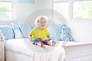 Child playing in bed. Kids room. Baby boy at home