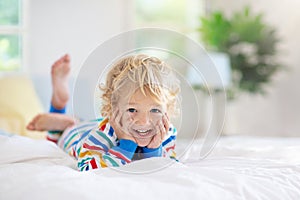 Child playing in bed. Kids room. Baby boy at home