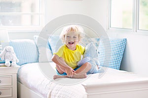 Child playing in bed. Kids room. Baby boy at home