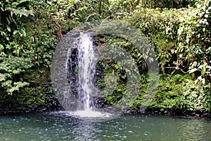 Child playing below a waterfall in the jungle in Ecuador