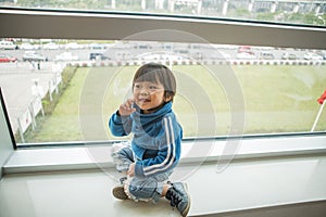 child playing in blue sportswear standing on a wide windowsill