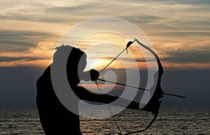 Child playing bow and arrow on the beach, Silhouette photo