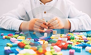 Child playing and building with colorful toy bricks, plastic blocks