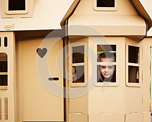 Child playing in a cardboard playhouse. Eco concept