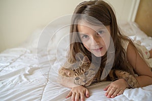 Child playing with cat on bed