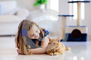 Child playing with cat at home. Kids and pets