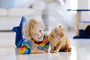 Child playing with cat at home. Kids and pets