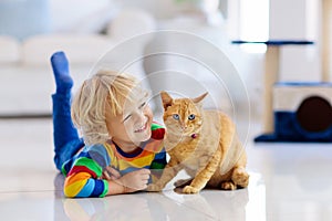 Child playing with cat at home. Kids and pets