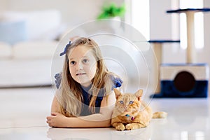 Child playing with cat at home. Kids and pets