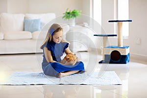 Child playing with cat at home. Kids and pets