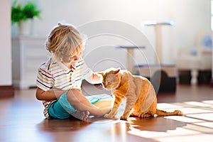 Child playing with cat at home. Kids and pets